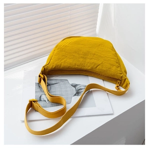 Detail of bright yellow nylon crescent crossbody bag with black zipper and fabric strap