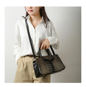 Vue détaillée du sac à main motif crocodile avec finitions dorées et pieds en métal