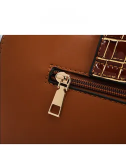 Détail d'un sac cabas en cuir marron avec motif crocodile et fermeture éclair dorée