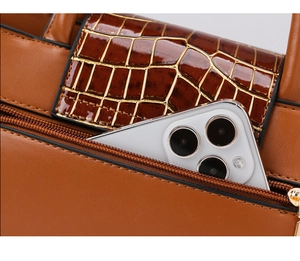 Détail d'un sac marron foncé en cuir de crocodile avec poche zippée pour smartphone
