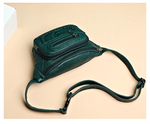 Detail of dark green textured leather waist bag with woven patterns and heart charm