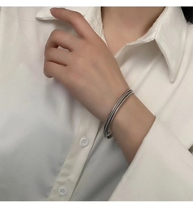 Close-up of a triple-intertwined silver titanium steel bangle on a female wrist
