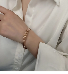 Detail of three-in-one rose gold stackable bangles featuring smooth and frosted textures