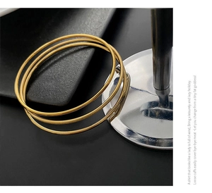Macro detail of minimalist triple-layered gold titanium steel bangles with smooth finish