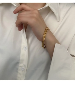 Close-up of triple-layered gold titanium steel rings on a woman's wrist in a formal setting