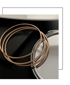 Macro shot of three stacked rose gold minimalist thin rings on a textured black base