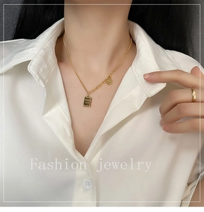 Detail of gold layered necklace featuring Good Luck pendant and smiley face charm
