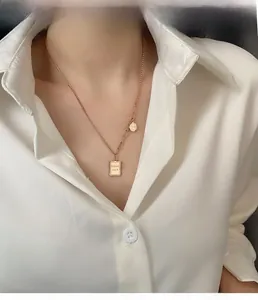 Detail of rose gold necklace with Good Luck rectangular plate and smile pendant on model