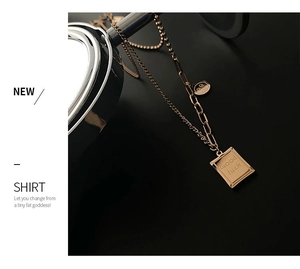 Detail of rose gold double layer titanium necklace featuring Good Luck square pendant