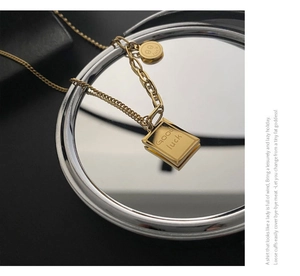 Close-up of gold titanium necklace with Good Luck pendant and smiley charm detail