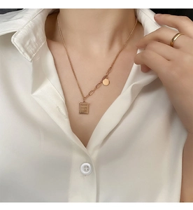 Detail of gold titanium steel necklace with Good Luck pendant on white shirt