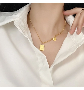 Detail of gold necklace with 'Good luck' pendant on a white shirt background