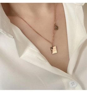Detail of gold titanium steel necklace with lucky pendants on a white shirt