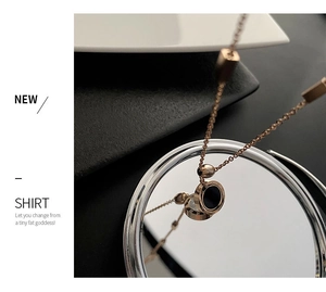Détail d'un collier en or rose avec pendentif chiffres romains reflété sur un miroir rond