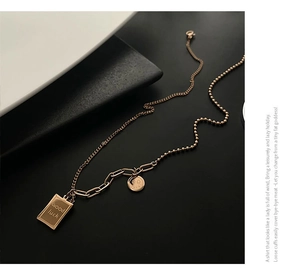 Detail of rose gold titanium necklace with Good Luck rectangle and smiley face pendants
