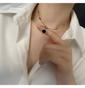 Détail du collier en or rose avec chiffres romains et pendentif noir sur un mannequin