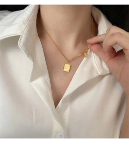 Detail of gold pendant necklace with Good luck engraving on a layered chain link