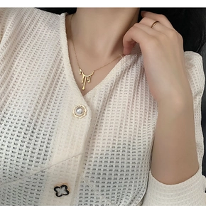 Détail d'un collier goutte de lave dorée sur mannequin avec bague minimaliste