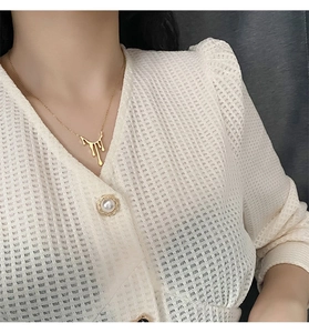 Gros plan du collier goutte de lave dorée porté par un mannequin au style élégant
