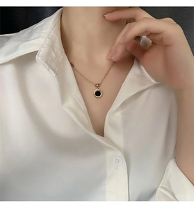 Détail du collier à chiffres romains en or rose avec insert noir sur le cou d'un mannequin