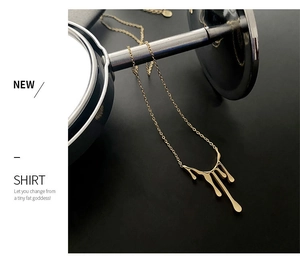 Détail du pendentif goutte dorée avec design de lave liquide sur chaîne en titane