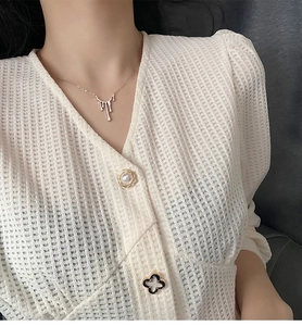 Détail du collier avec pendentif lave argentée porté sur un gilet en maille gaufrée