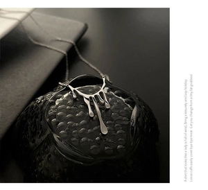 Gros plan du collier avec pendentif lave liquide en argent sur un support noir texturé