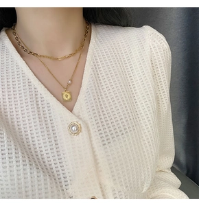 Close-up of double-layer gold necklace featuring a coin portrait pendant and a small pearl