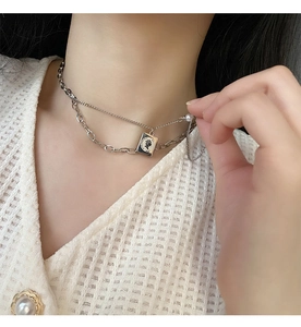Detail of layered titanium steel necklace with portrait coin pendant and pearl on model