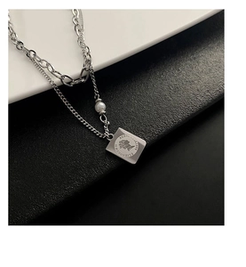 Detail of silver double-layer necklace featuring a square coin pendant and a white pearl