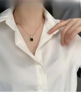 Detailed view of a gold titanium necklace featuring a geometric black square pendant on a model