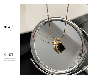 Artistic reflection of a gold titanium necklace with a minimalist black square pendant