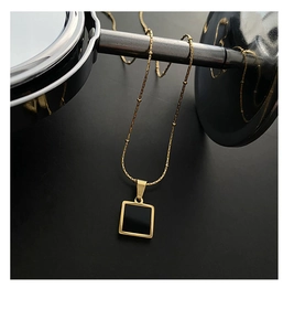 Detail of gold geometric square pendant on a beaded chain with black enamel finish