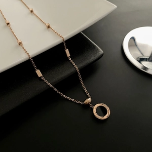 Collier en or rose avec pendentif anneau à chiffres romains et détails géométriques