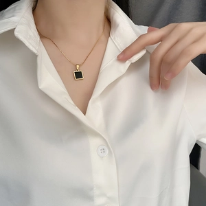 Elegant gold titanium steel necklace with square black pendant on a female model