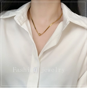 Close-up of minimalist gold snake chain necklace with a polished sphere pendant on a model