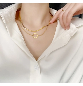 Gros plan d'un collier doré double couche avec pendentif anneau sur une chemise