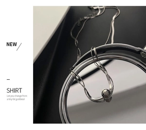 Macro shot of silver double-layer necklace with smooth spherical metal pendant detail