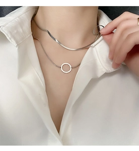 Gros plan d'un collier double épaisseur en acier titane argenté avec pendentif en O