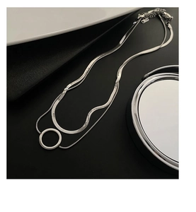 Vue macro d'un collier superposé argenté avec pendentif rond sur fond noir élégant