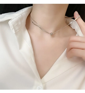 Close-up of double layer silver necklace with snake chain and polished bead pendant
