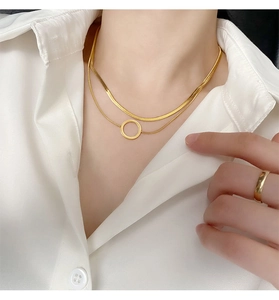 Gros plan sur un collier double rangée doré avec pendentif rond sur chemise blanche