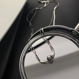 Minimalist silver double-layer titanium necklace with sleek metal ball pendant on mirror