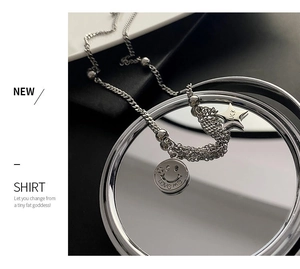 Close-up of silver titanium steel necklace featuring Love Me smiley and Luck star charms