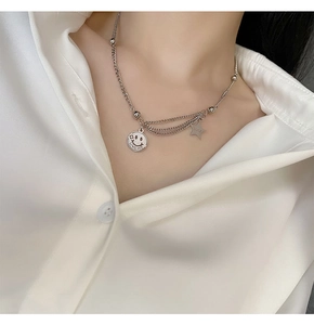 Detail of silver layered necklace with smiley face love me and lucky star pendants