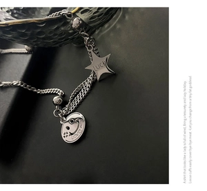 Macro detail of silver layered chain necklace with lucky star and smile face pendants