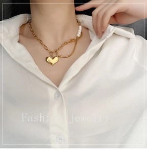 Detail of gold heart pendant necklace with elegant pearl stitching on minimalist chain