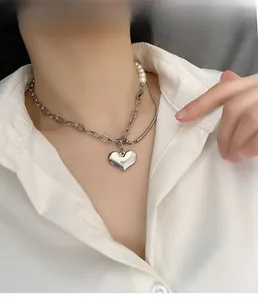Detailed view of asymmetric heart pendant necklace with pearls and silver chain on model