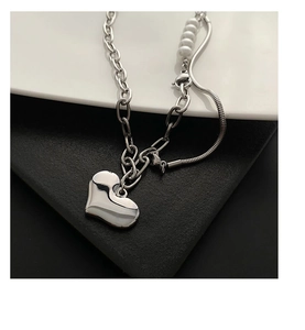 Macro shot of silver-toned heart pendant and pearl splicing chain with polished finish