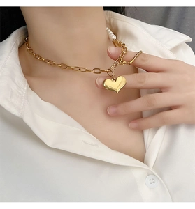 Detail of titanium heart necklace featuring gold chain and pearl splicing on a model neck